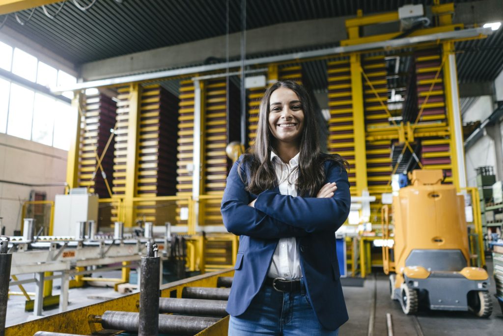 Confident woman standing in logistics center, with arms crossed